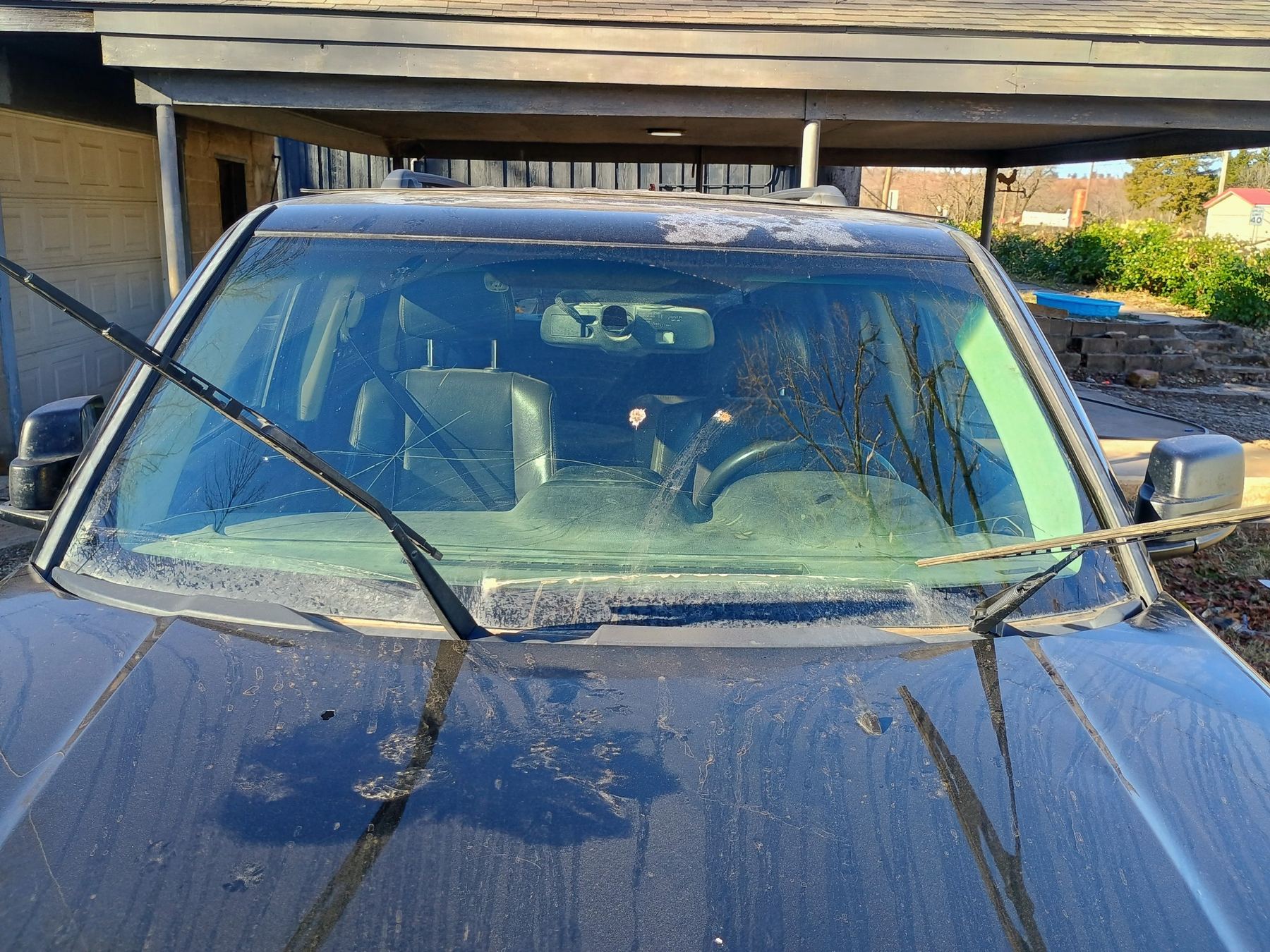 Dark pickup under a carport with a badly cracked windshield