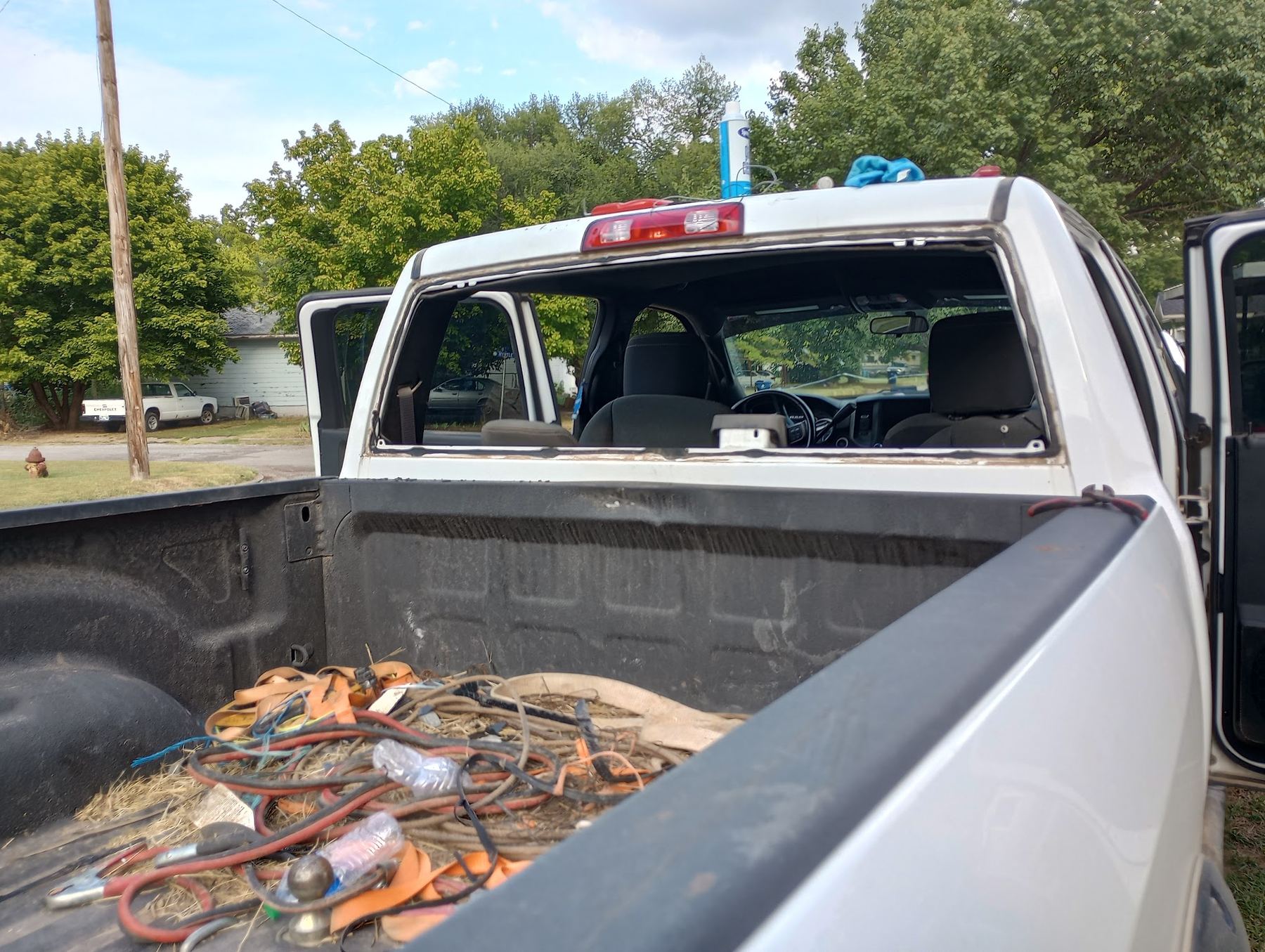 White pickup outdoors with the back glass out and the doors open