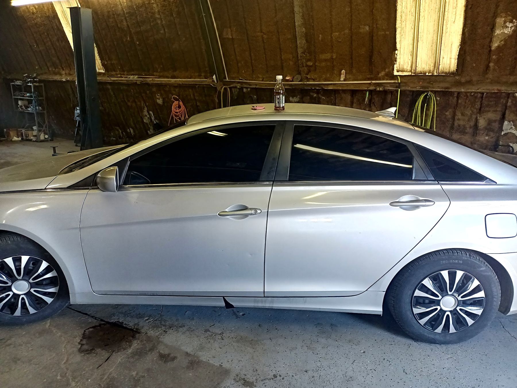 Silver sedan inside a wood-walled shop bay