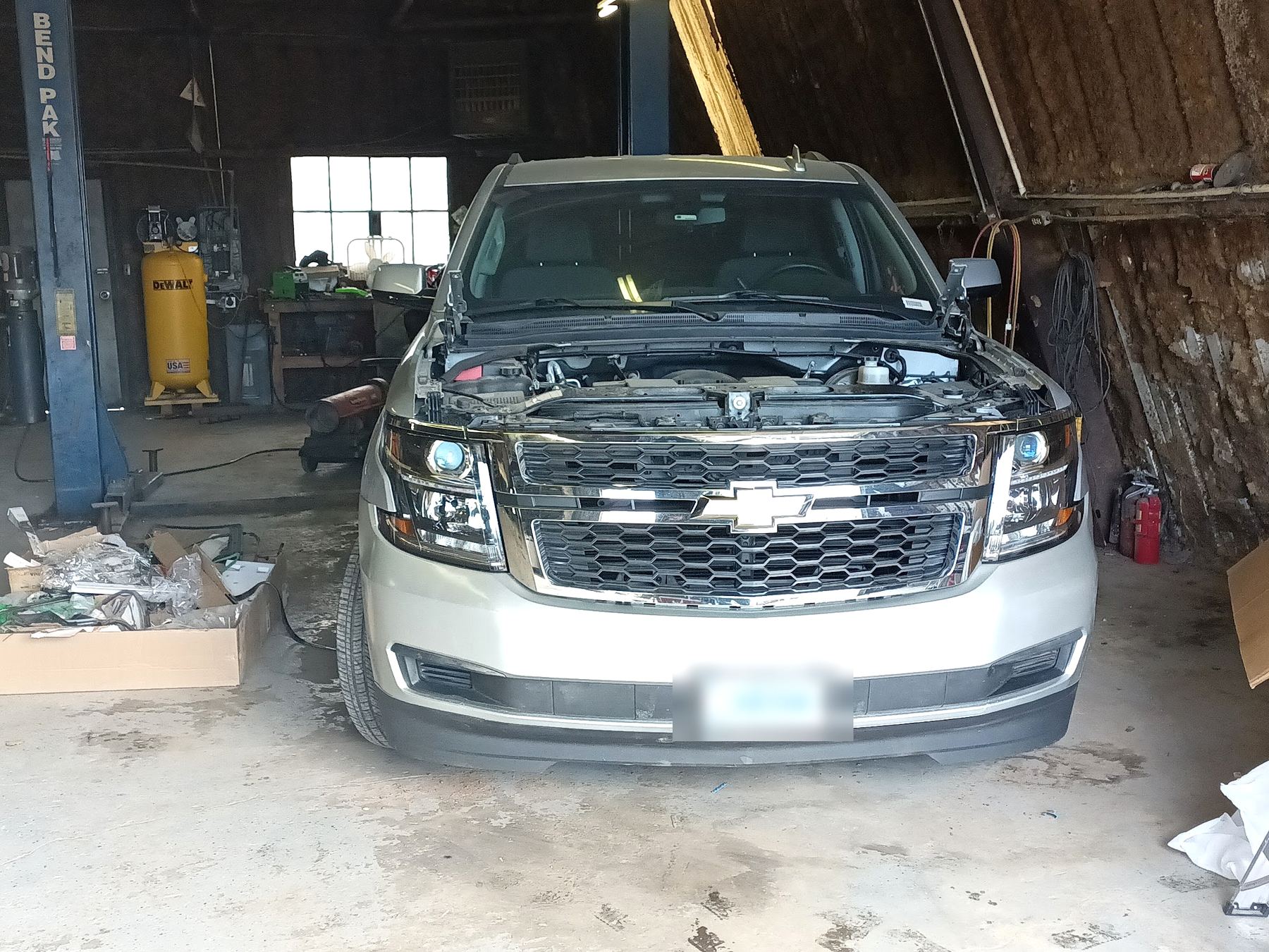 Silver Chevy Tahoe in a wood-walled shop bay